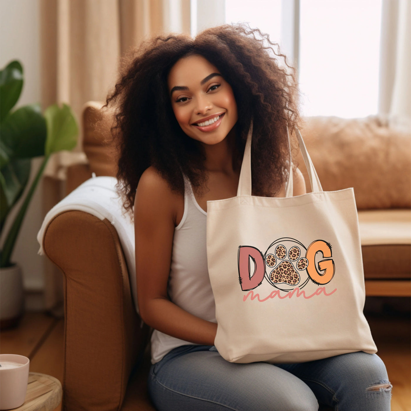 Woman smiling while holding a "Dog Mama" tote bag on a cozy living room couch