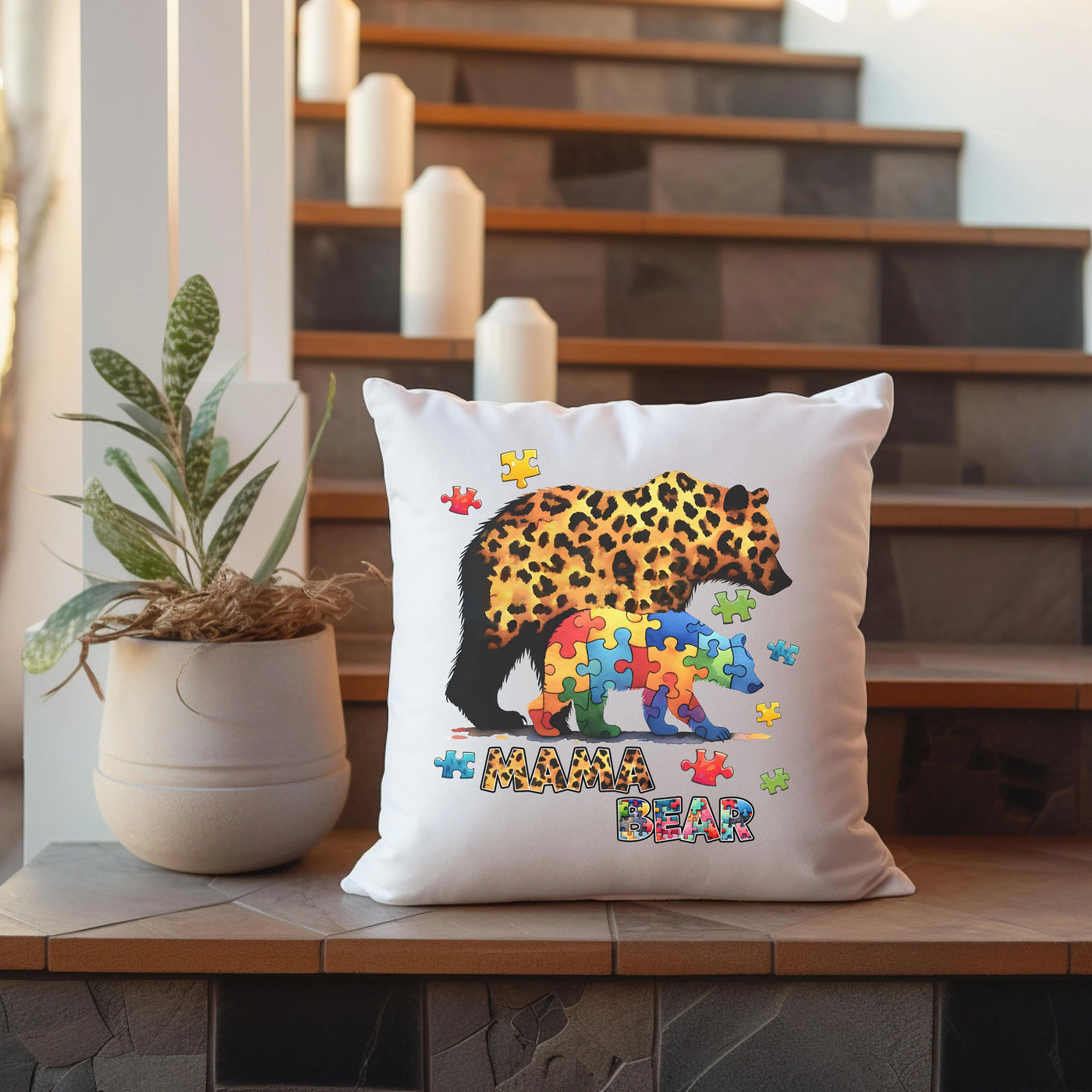 Decorative pillow featuring a leopard-print bear and cubs in puzzle patterns with "Mama Bear" text, placed on stairs with candles and a plant.