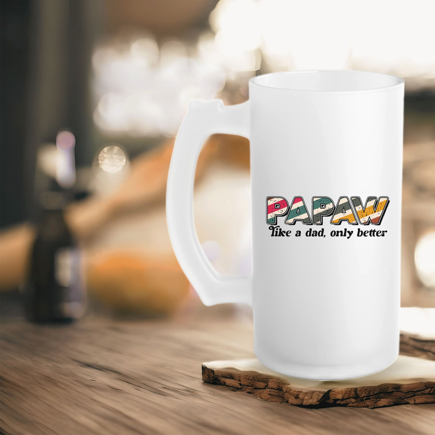 White ceramic mug with "PAPAW Like a dad, only better" text on a wooden surface, blurred background.