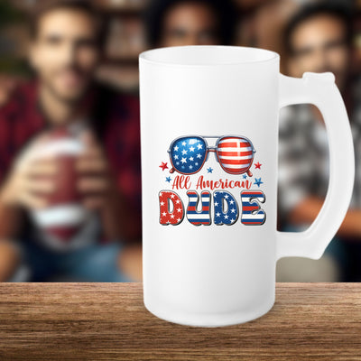 Frosted beer mug with "All American Dude" design featuring sunglasses with American flag, on a wooden table with blurred friends in the background