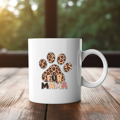 White mug with leopard print paw and "Fur Mama" text on wooden table with green background.