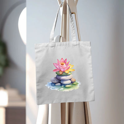 a white bag with a pink flower sitting on top of a pile of rocks