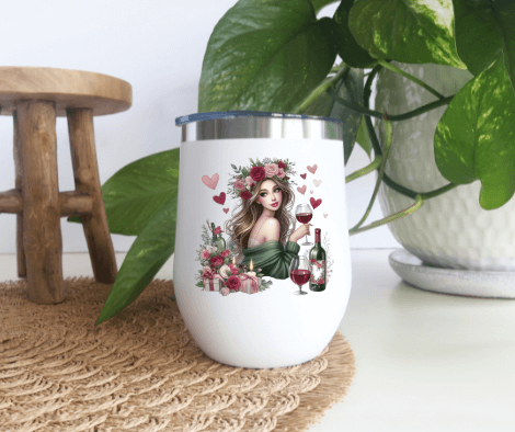 Decorative wine tumbler featuring a woman with flowers, hearts, and wine glasses, placed on a table with green plants in the background.