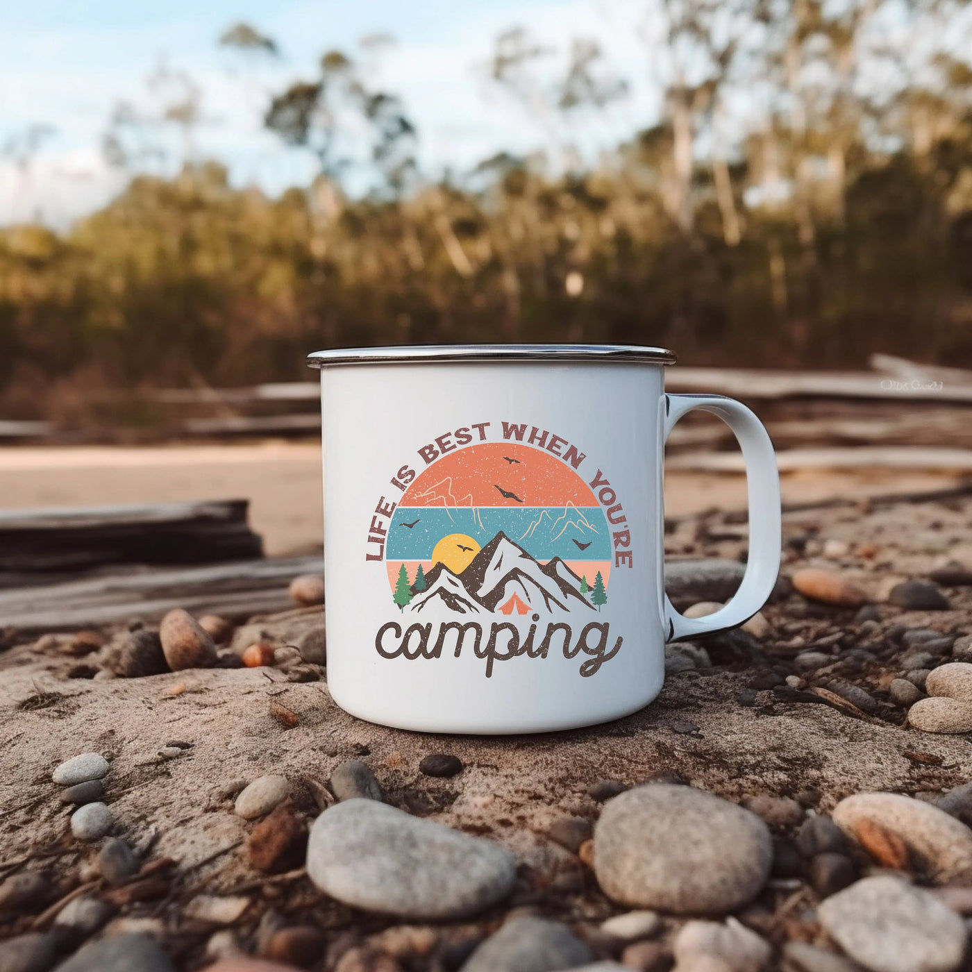 a white camp mug sitting on top of a pile of rocks