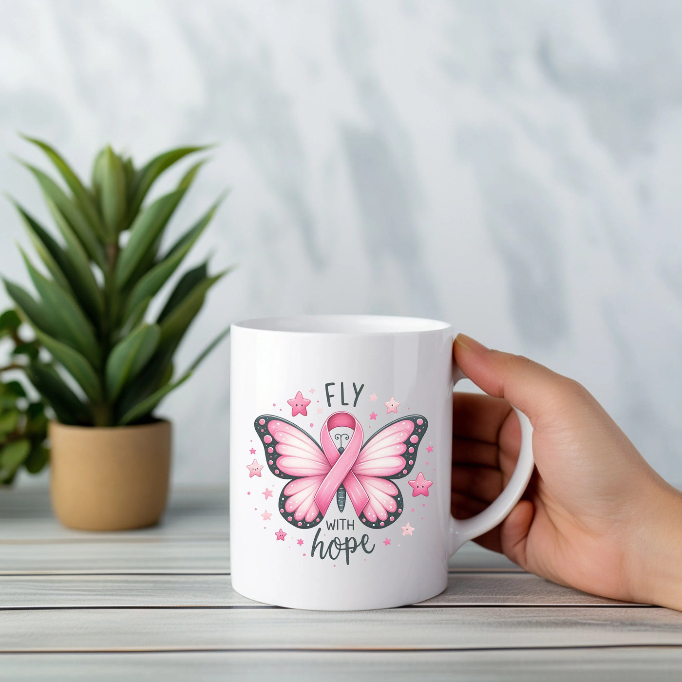 a person holding a coffee mug with a pink ribbon on it