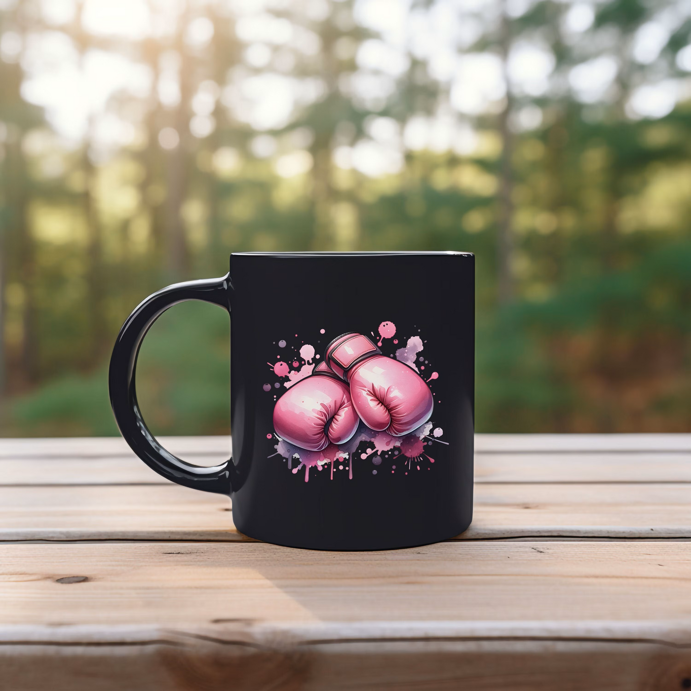 Black mug with pink boxing gloves illustration on a wooden table outdoors with blurred forest background