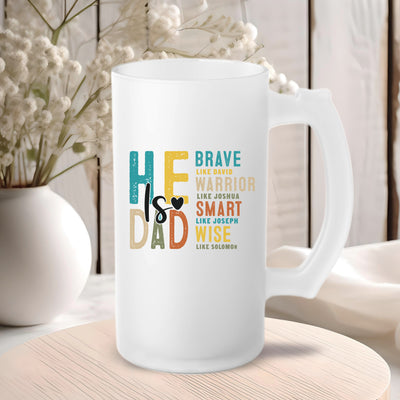 White mug with colorful text "He's Dad - Brave like David, Warrior like Joshua, Smart like Joseph, Wise like Solomon" on a wooden table