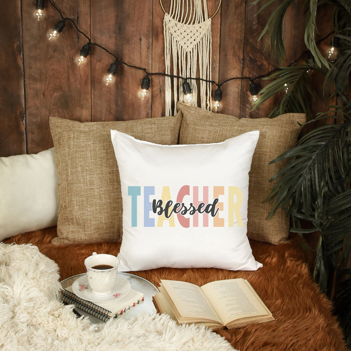 a pillow that says teacher on it next to a cup of coffee