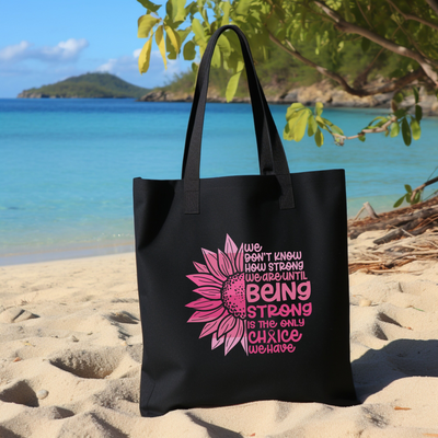 a black bag with a pink flower on the beach