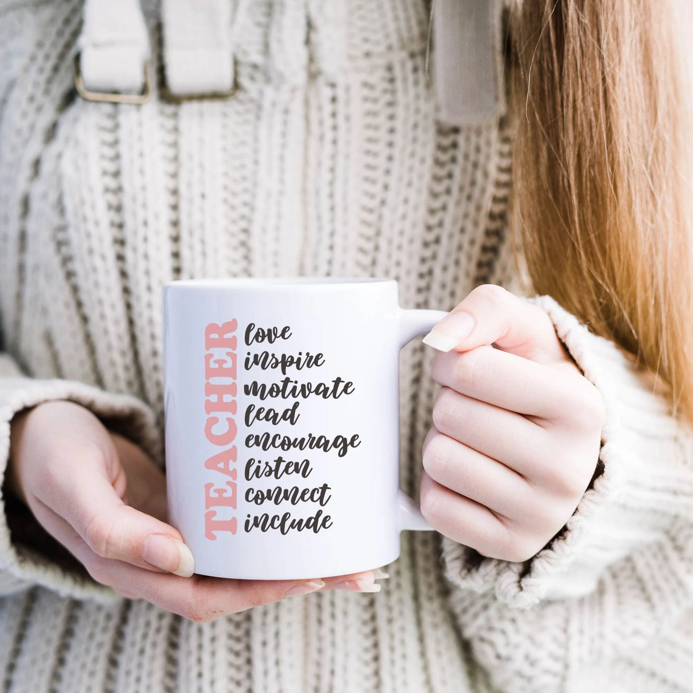 a woman holding a white coffee mug with the words teacher on it