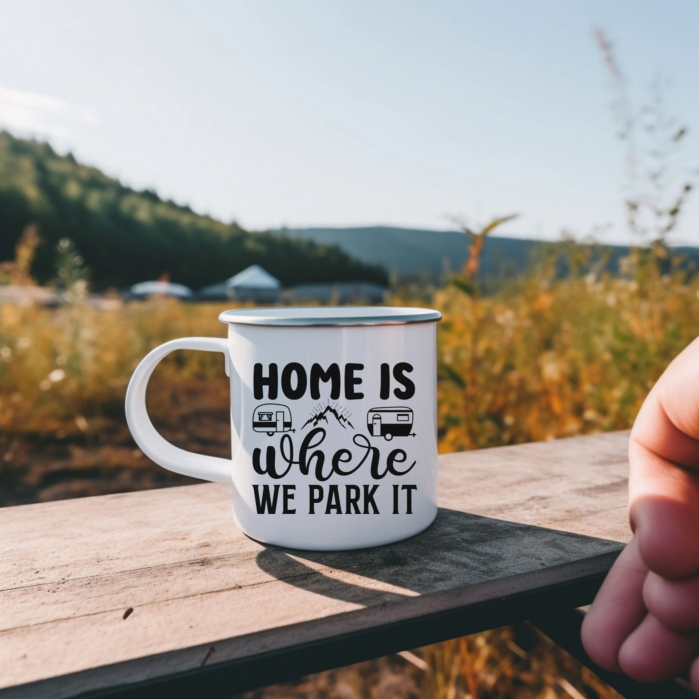 a hand holding a coffee mug that says home is where we park it