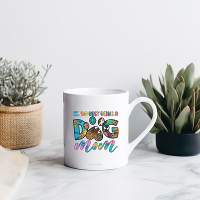 a coffee mug sitting on a table next to a potted plant