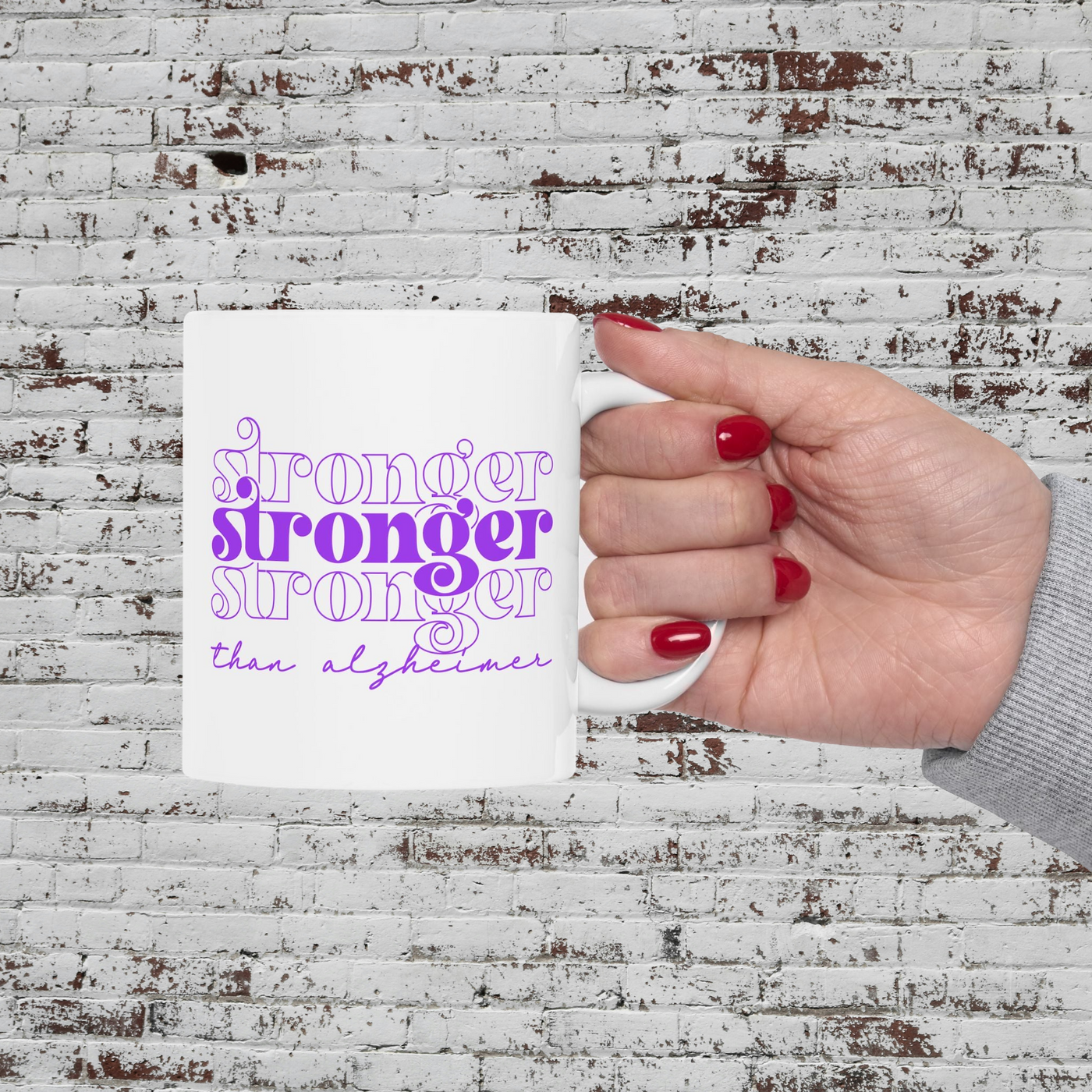 a woman's hand holding a white coffee mug with purple lettering