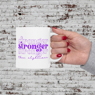 a woman's hand holding a white coffee mug with purple lettering