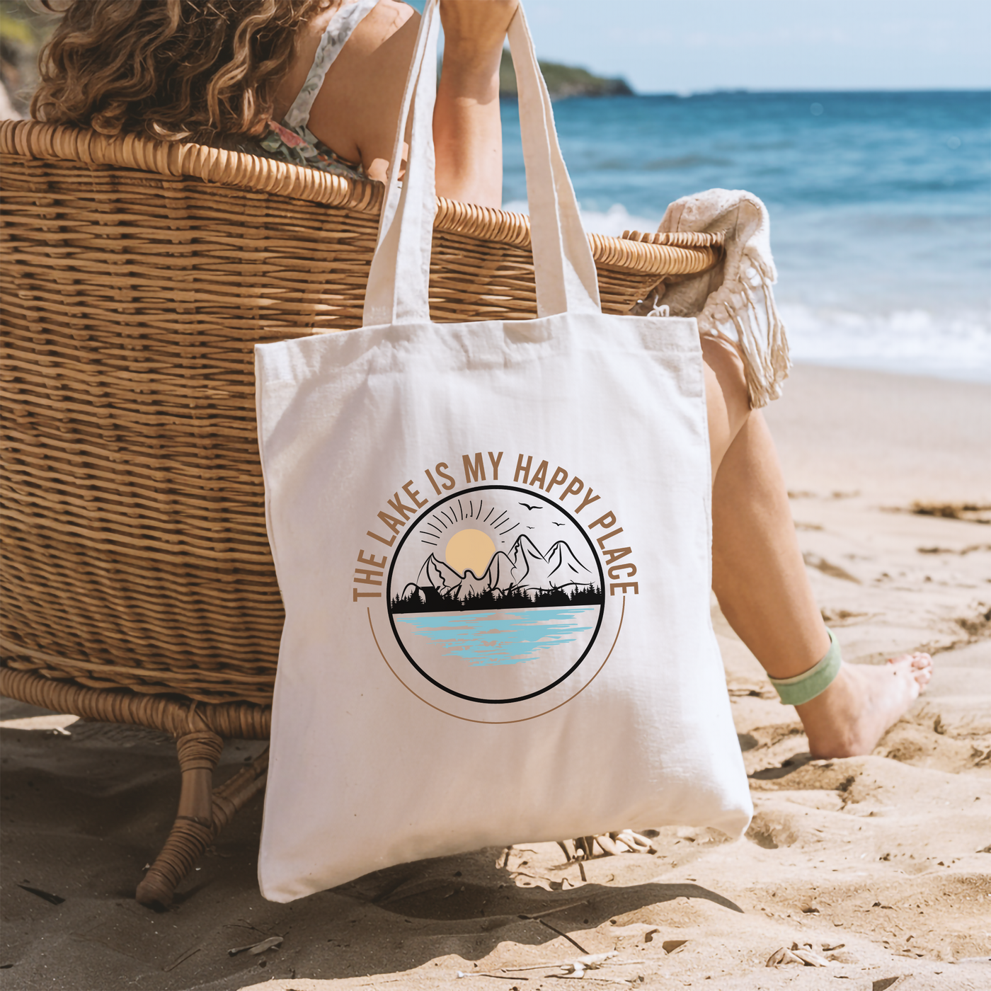 a woman sitting in a chair on the beach with a tote bag