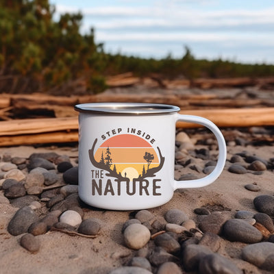 a white camp mug sitting on top of a pile of rocks