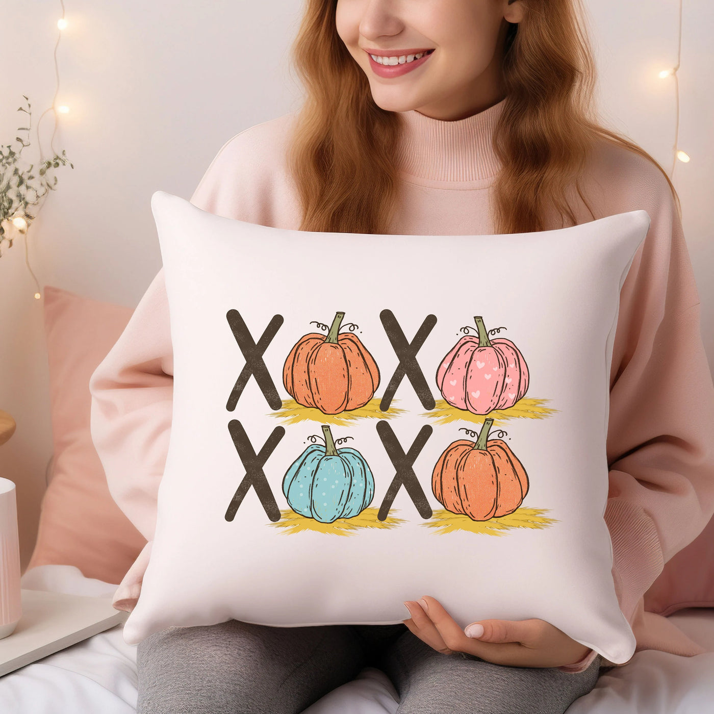 a woman sitting on a bed holding a pillow with four pumpkins on it