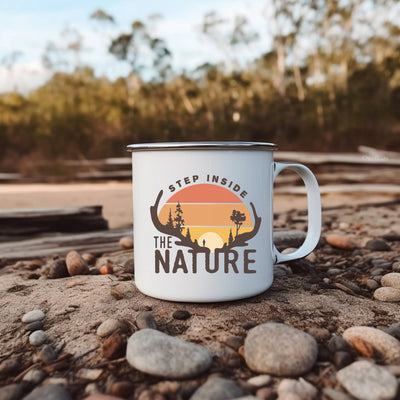 a campfire mug sitting on a rocky beach