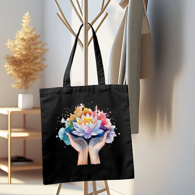 a black tote bag with a picture of two hands holding a flower