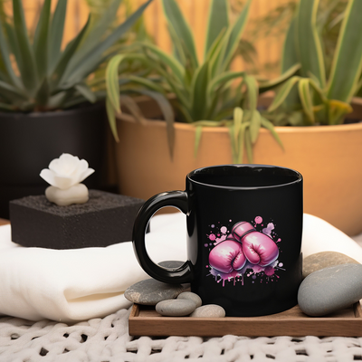 a black coffee mug with pink boxing gloves on it