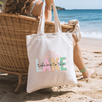 a woman sitting in a chair on the beach with a tote bag