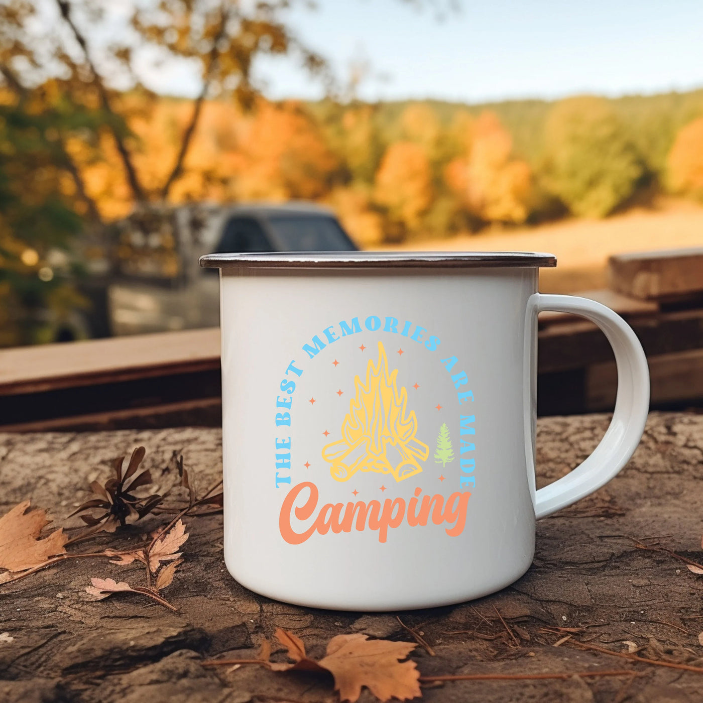 a campfire mug sitting on the ground next to leaves