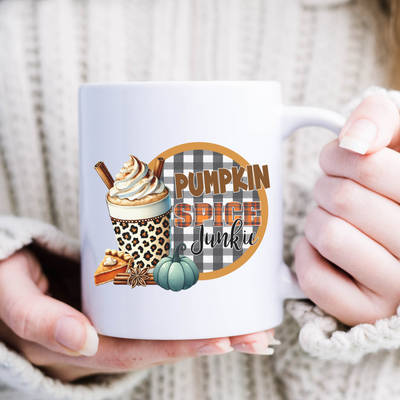 a woman holding a coffee mug with a pumpkin spice design