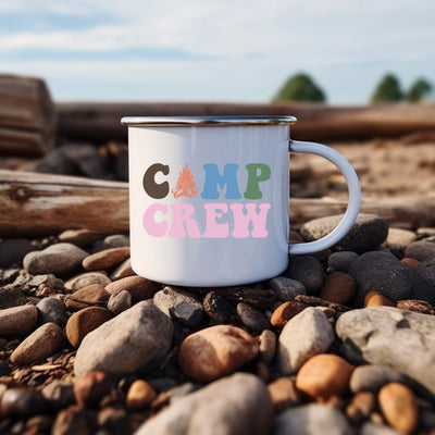 a camp crew coffee mug sitting on some rocks