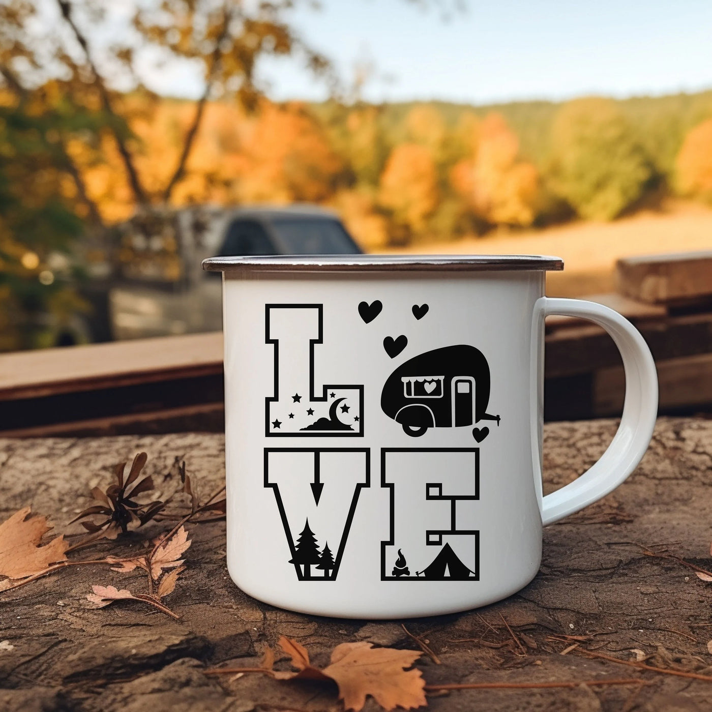 a camper mug sitting on the ground next to leaves