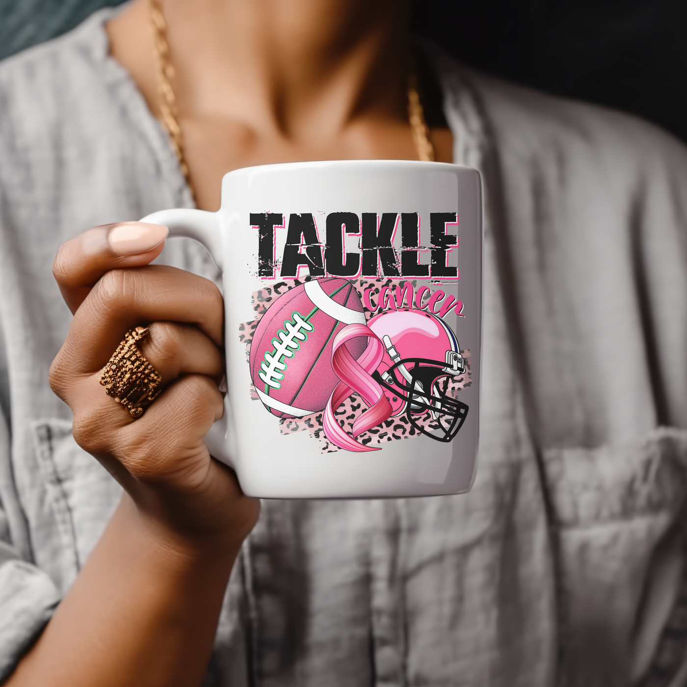 a woman holding a coffee mug with a pink ribbon on it