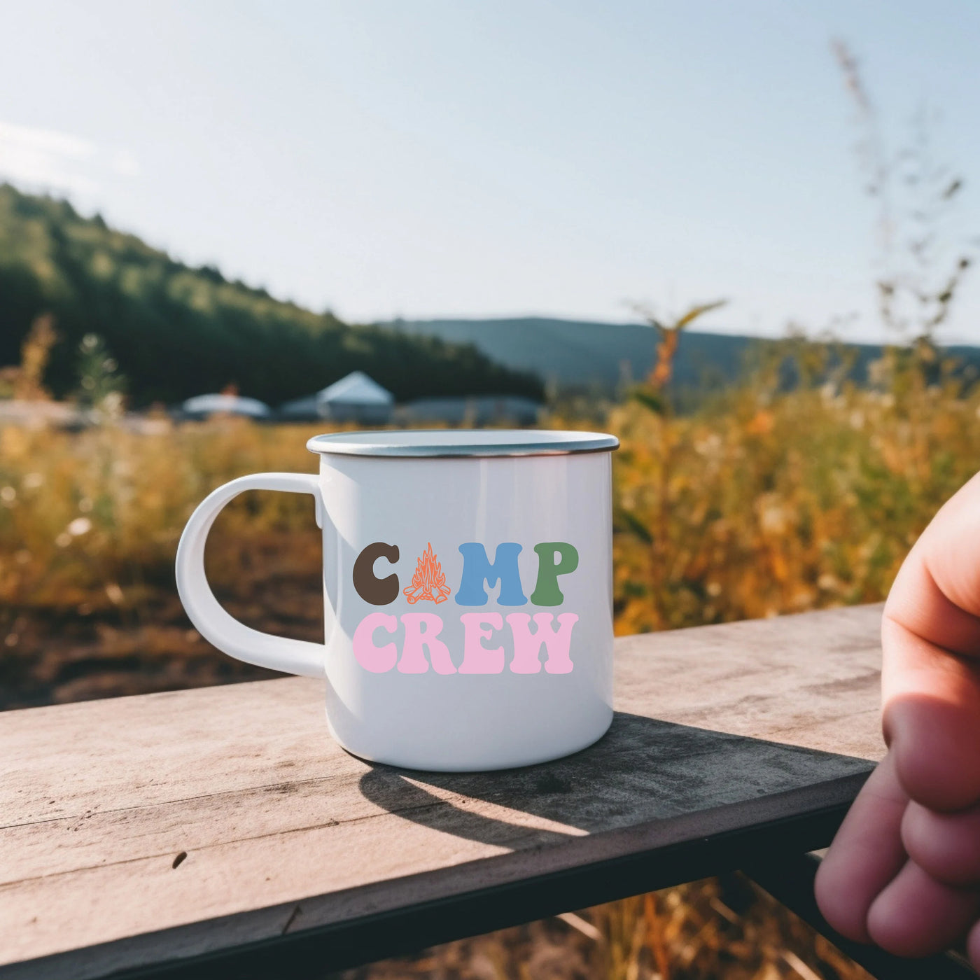 a camp crew coffee mug sitting on a picnic table