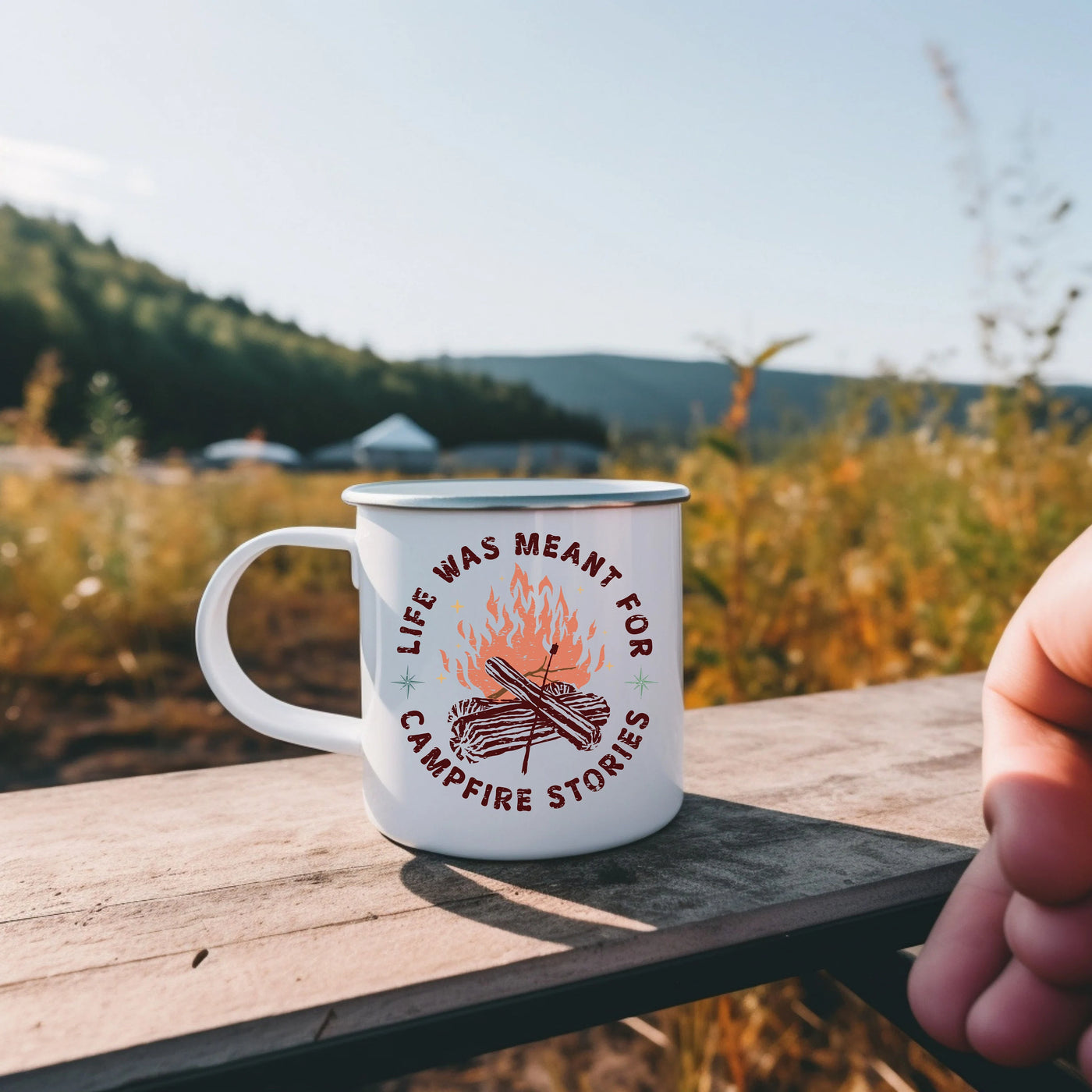 a person holding a coffee mug with a campfire stick on it