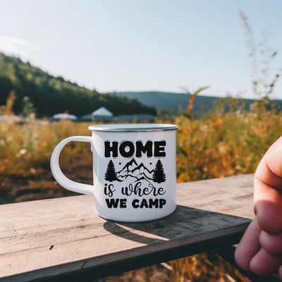 a hand holding a coffee mug with the words home is where we camp