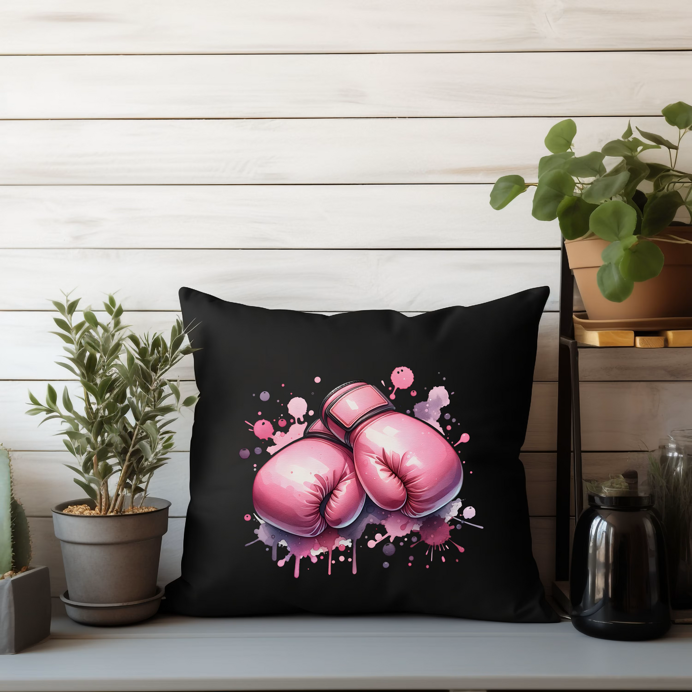 a black pillow with pink boxing gloves on it