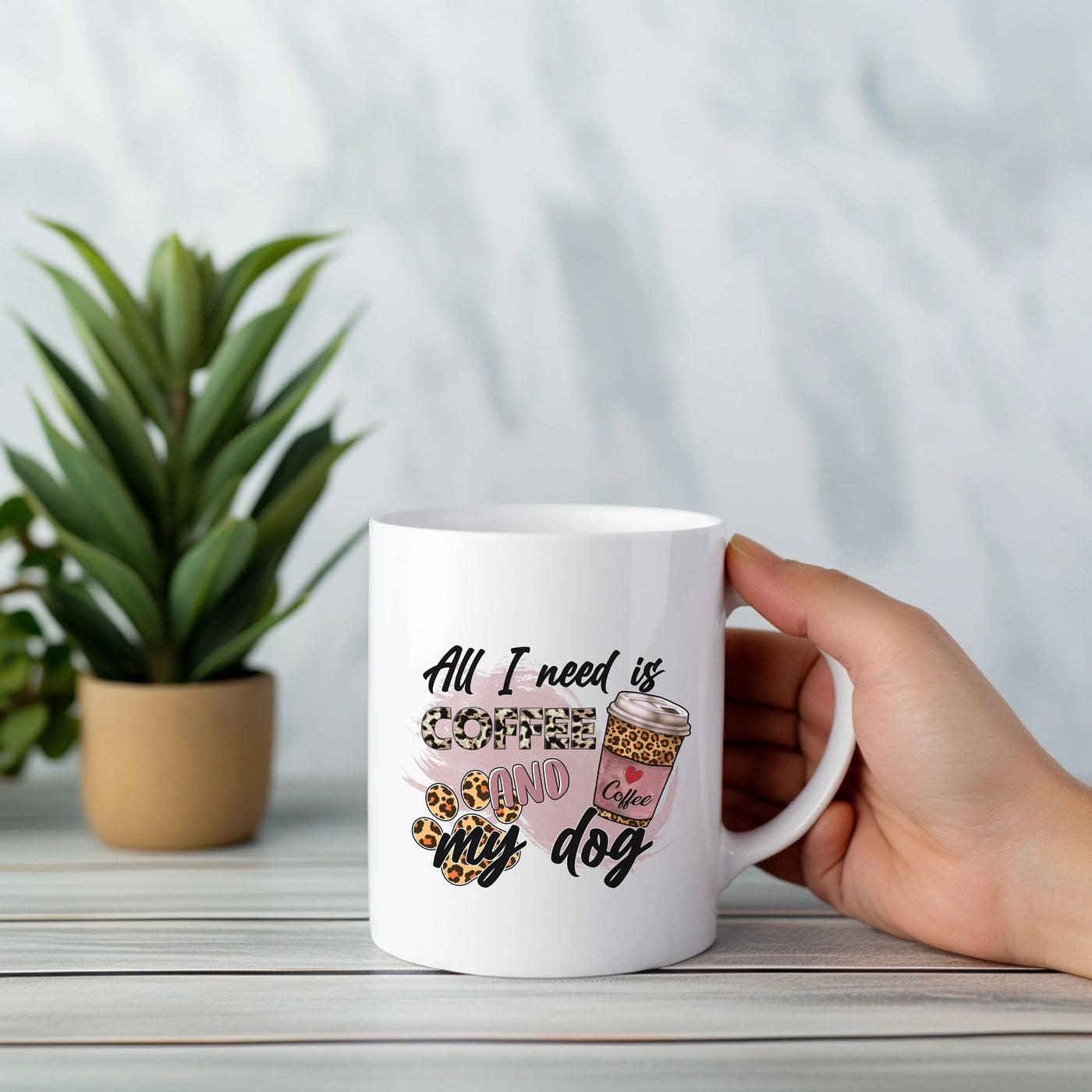 a person holding a coffee mug with a plant in the background