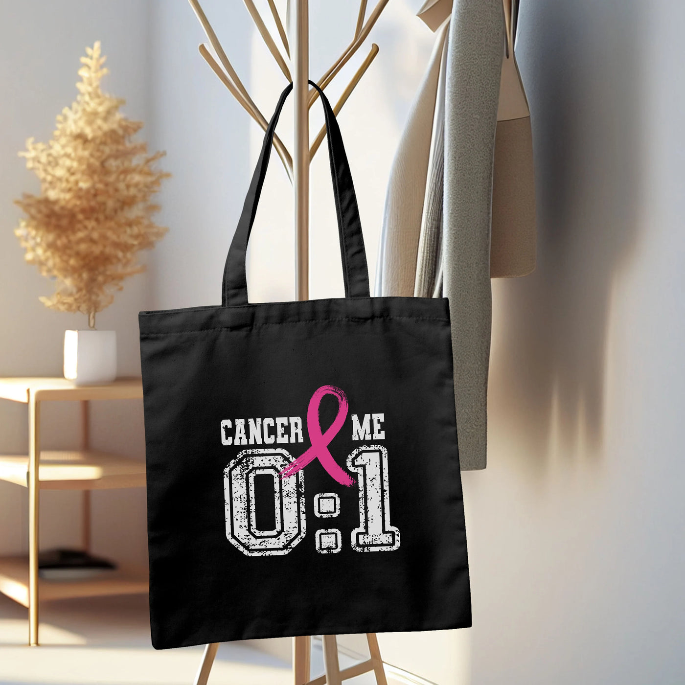 a black tote bag with a pink ribbon on it