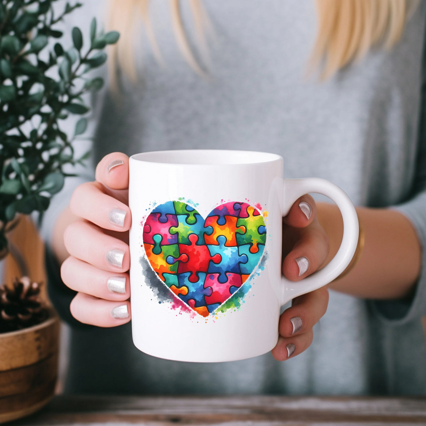 a woman holding a coffee mug with a puzzle heart on it