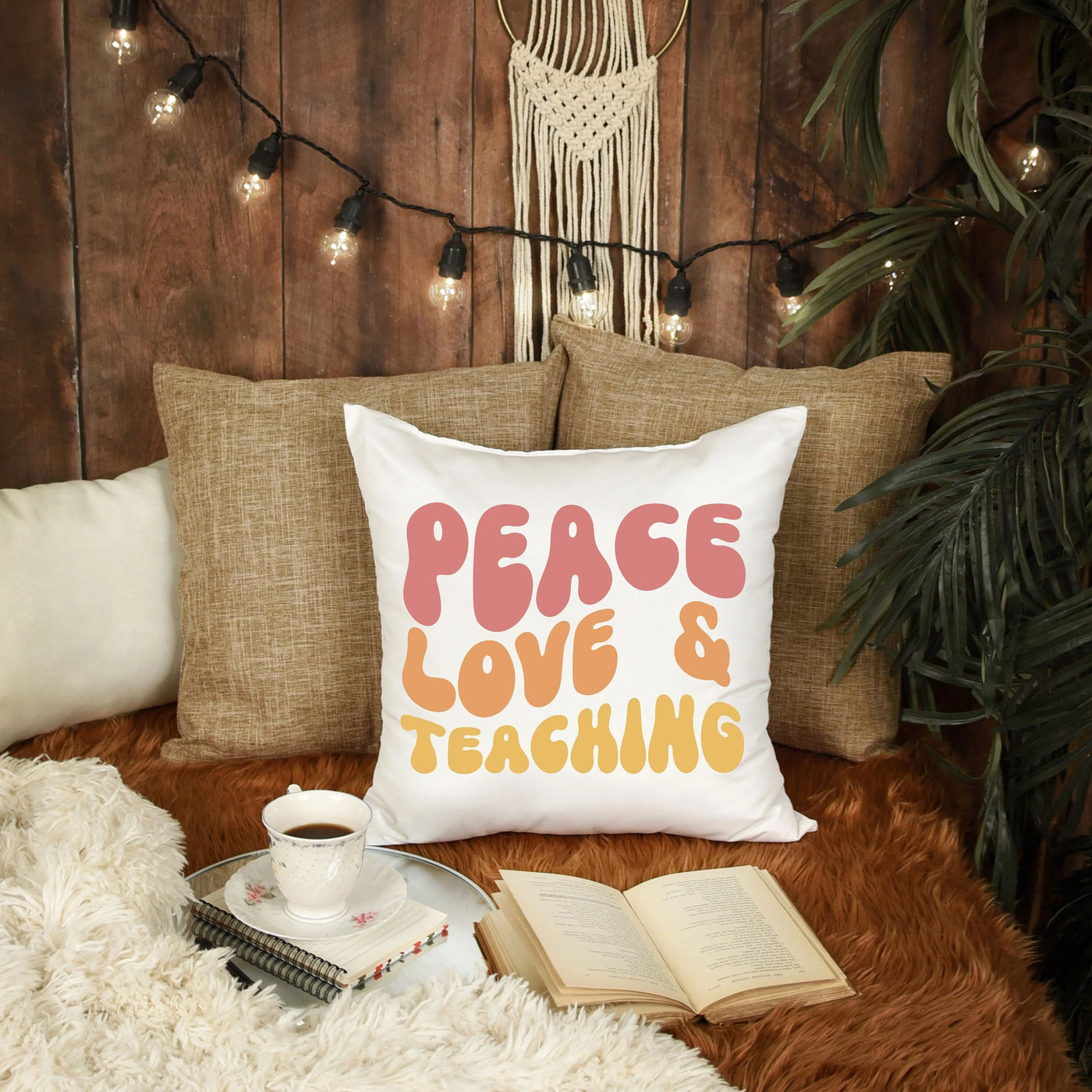 a pillow that says peace love and teaching next to a cup of coffee