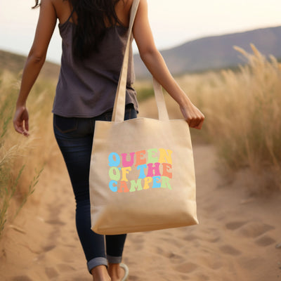 a woman carrying a tote bag that says queen of the summer