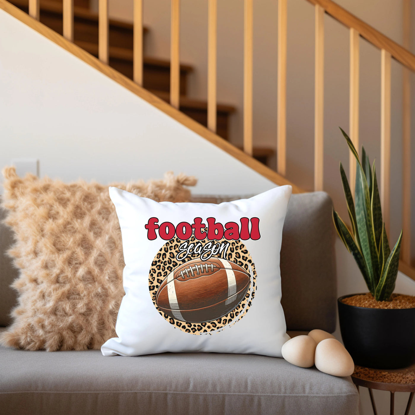 a football pillow sitting on a couch next to a potted plant