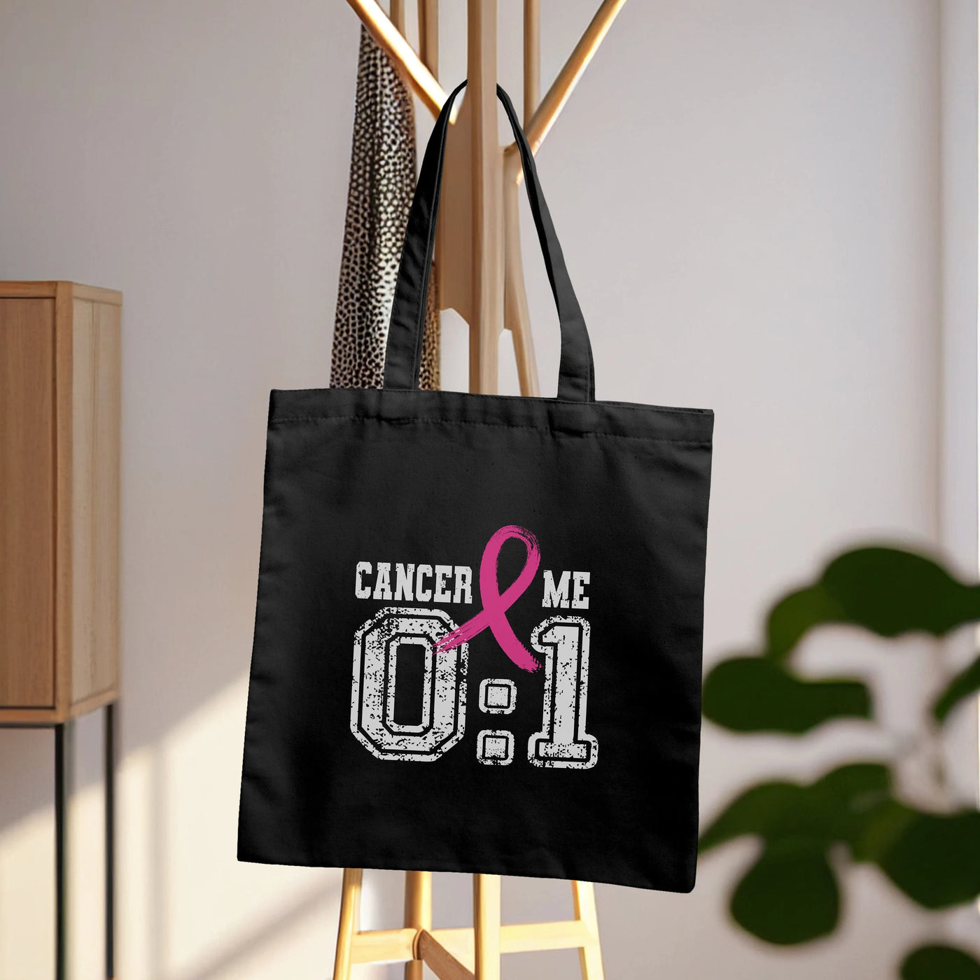 a black tote bag with a pink ribbon on it