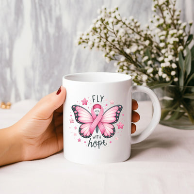 a woman holding a coffee mug with a pink ribbon on it