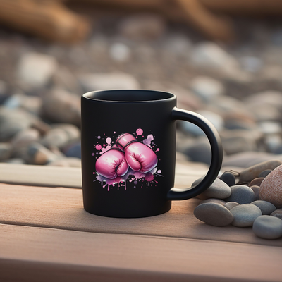 a black coffee mug with pink boxing gloves on it