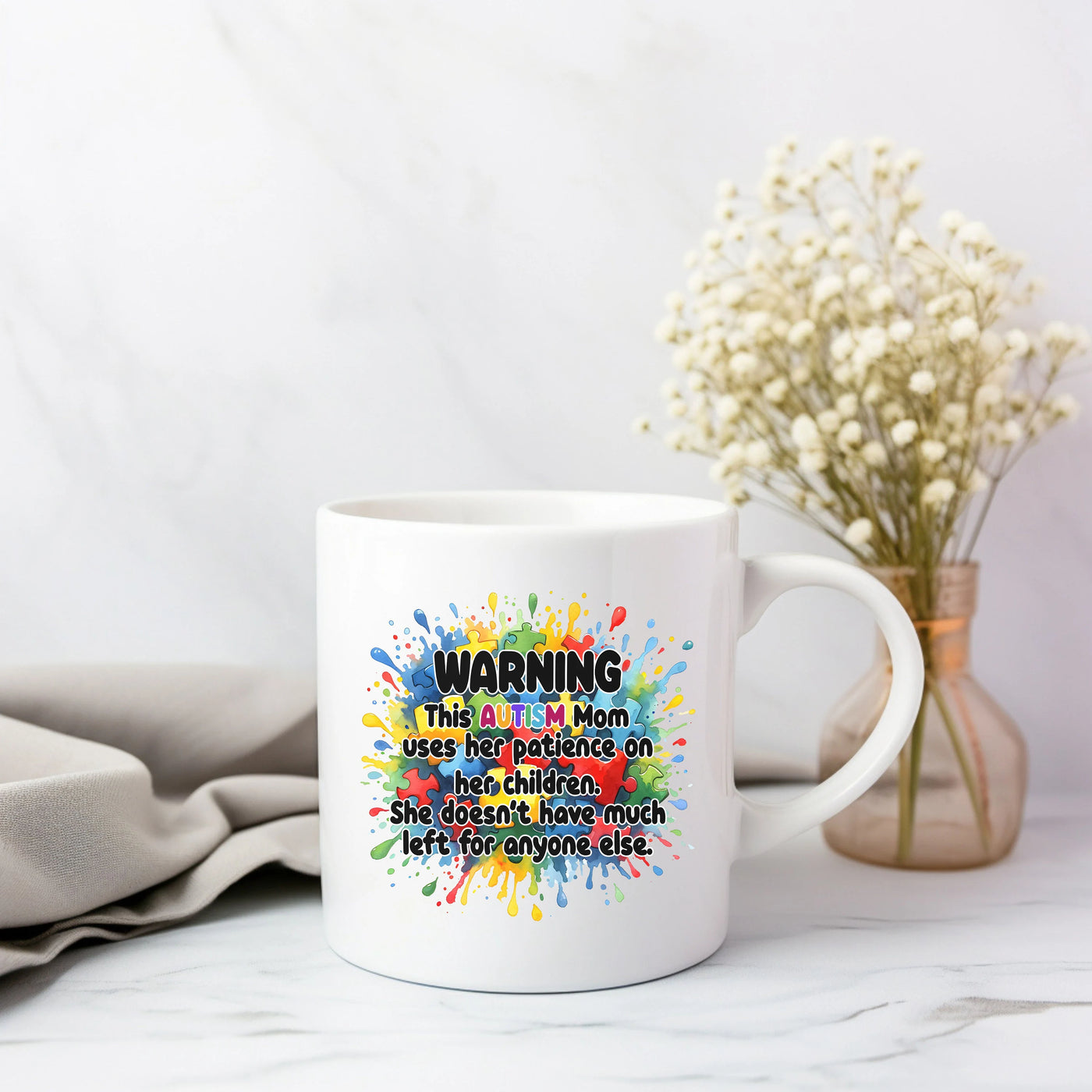 a coffee mug sitting on a table next to a vase with flowers