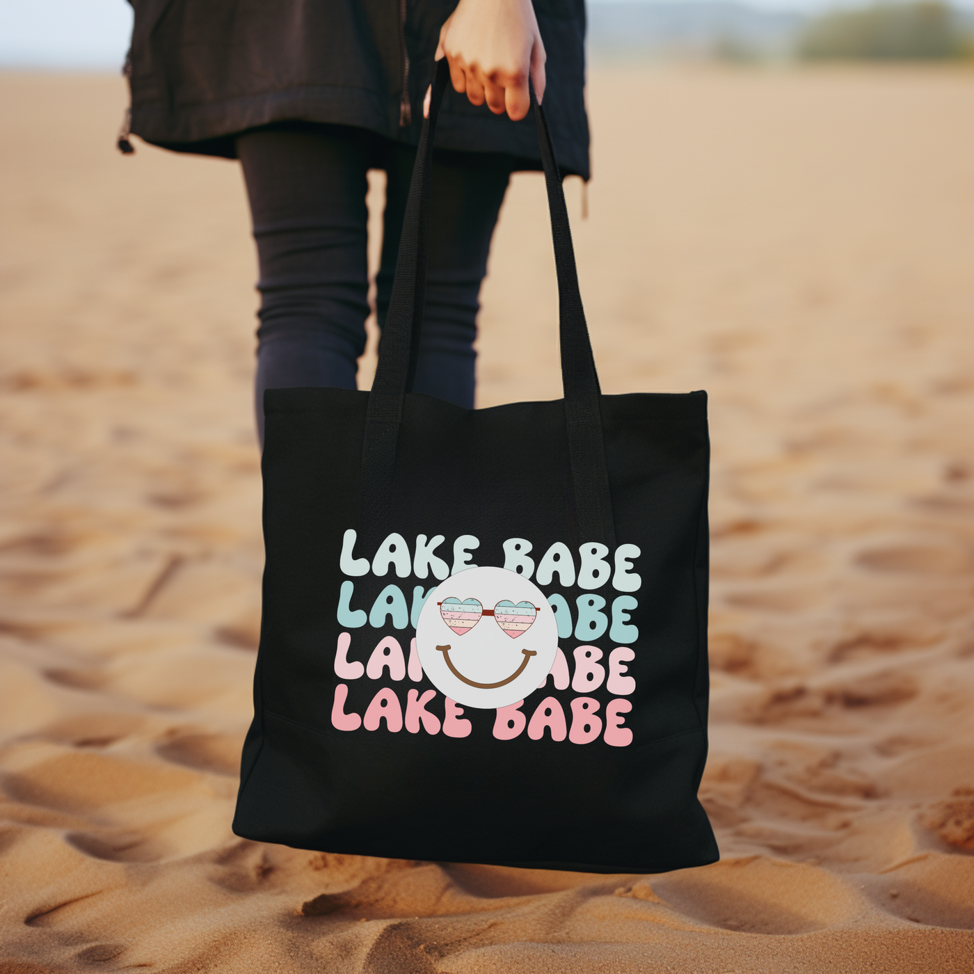 a woman carrying a black tote bag in the sand