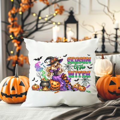 a white pillow with a witch and pumpkins on it