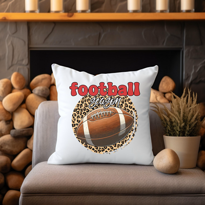 a football pillow sitting on top of a couch next to a potted plant