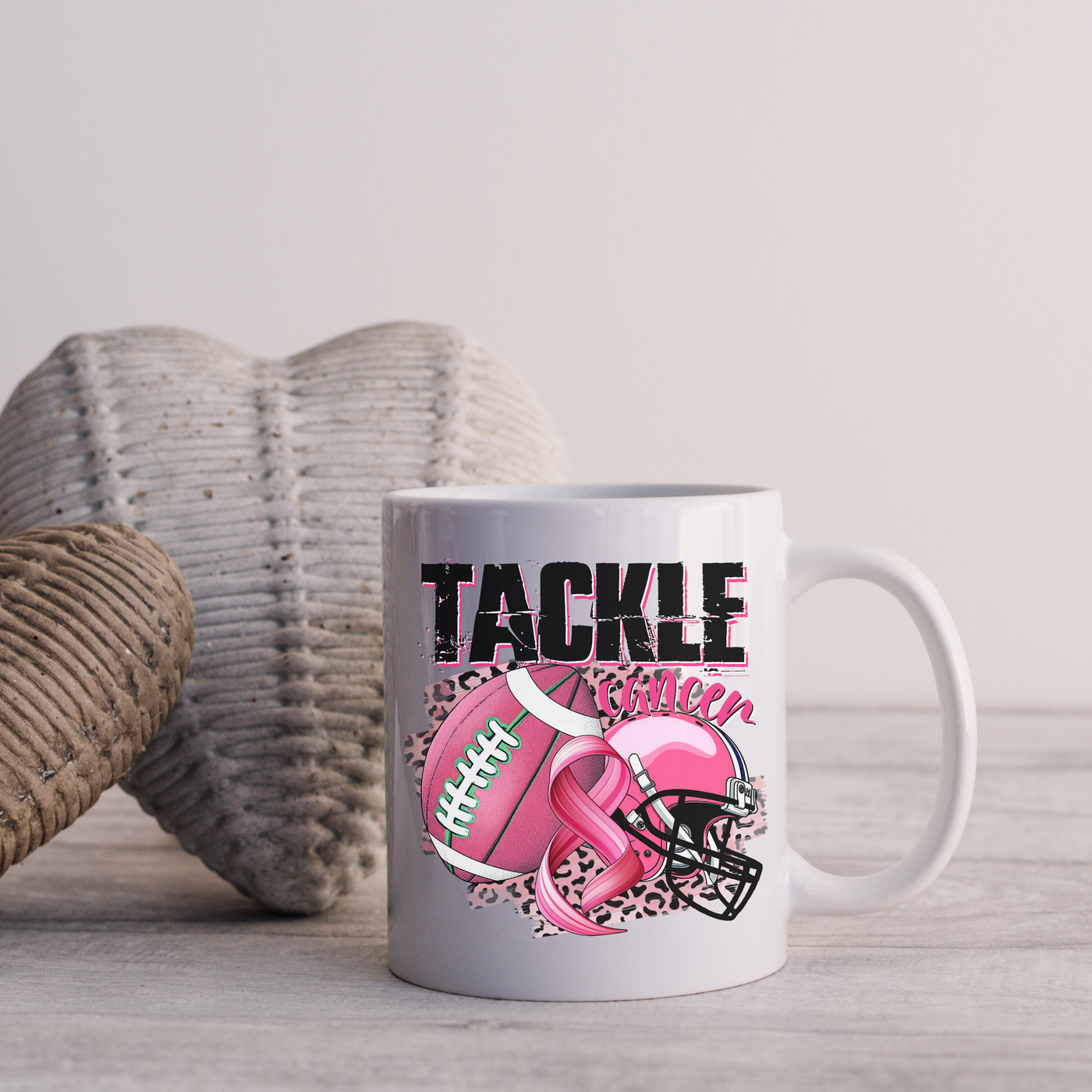 a white coffee mug with a pink ribbon and a football on it