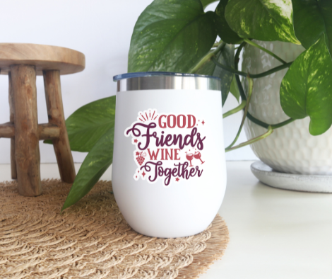 a white coffee cup sitting on top of a table next to a potted plant