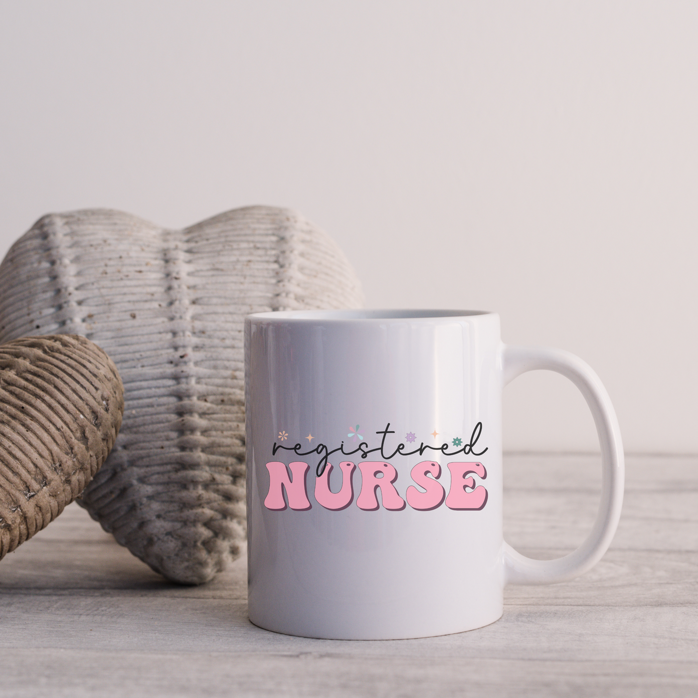 a white coffee mug sitting next to a knitted heart